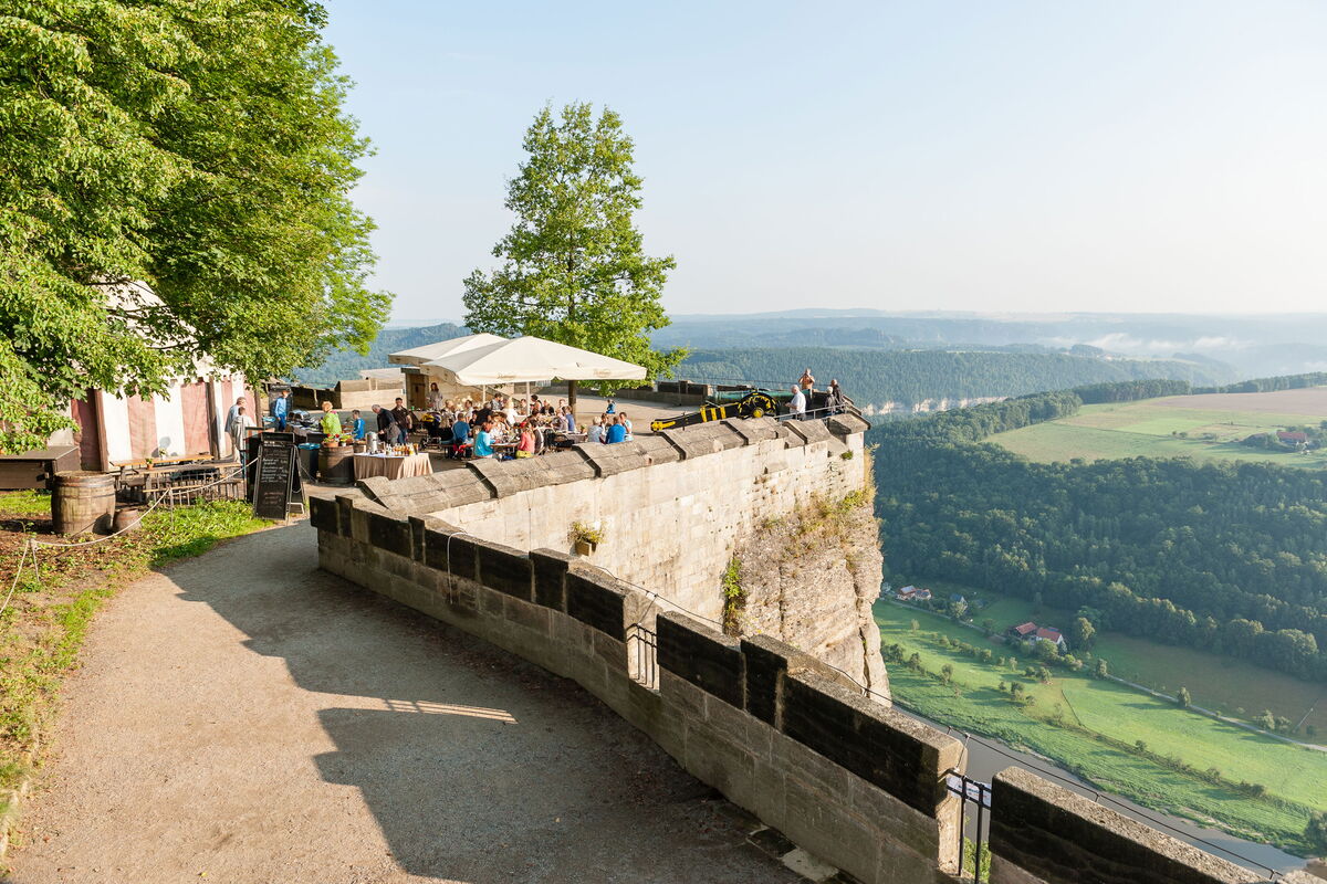 Blick auf die Sitzgruppen und Sonnenschirme und die Eiche am Blitzeichenplateau sowie ins Blick ins Elbtal